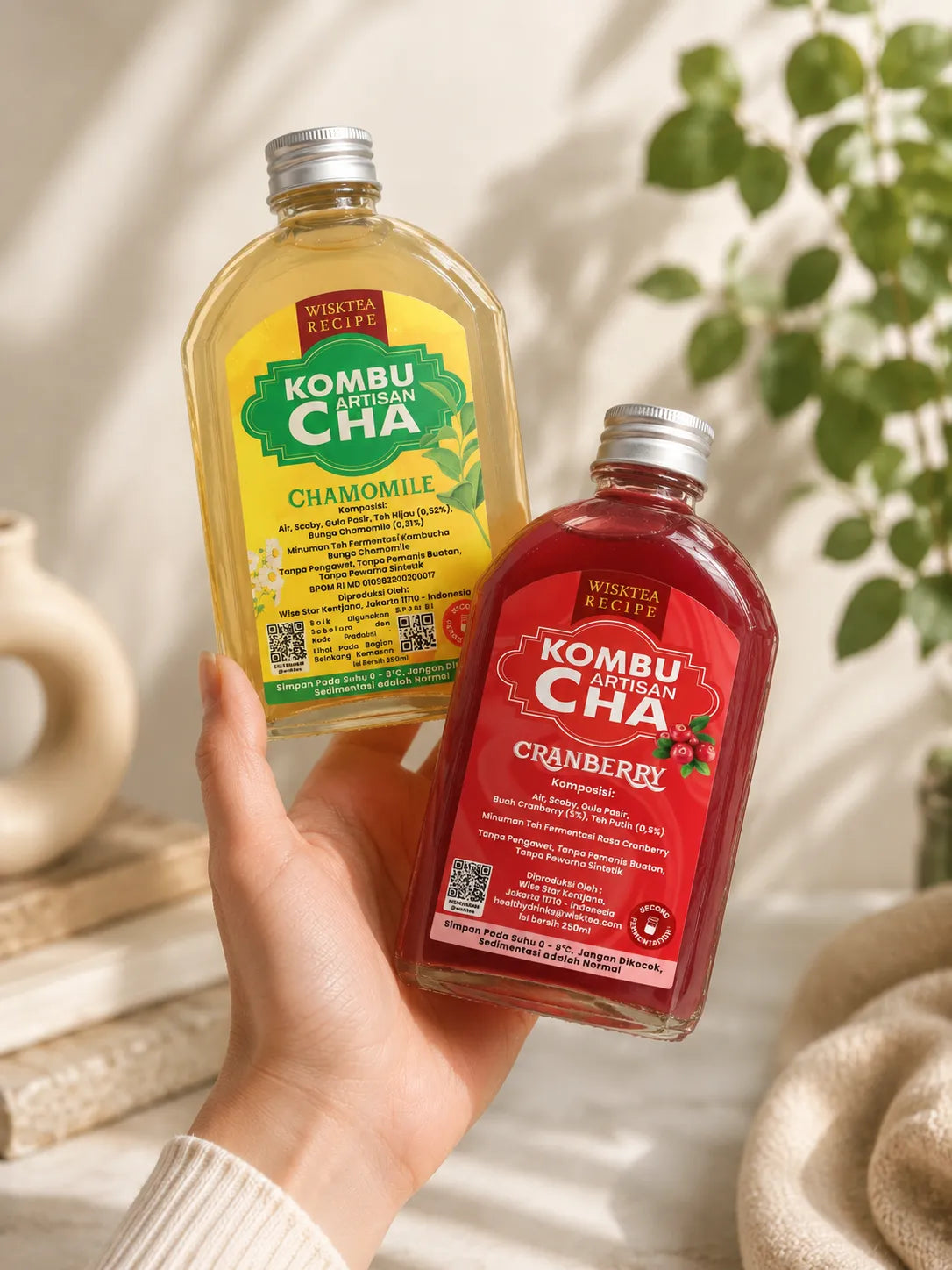 Hand holding WiskTea Kombucha Chamomile and Cranberry flavours against a calming wellness-inspired background, showcasing naturally brewed kombucha for daily refreshment.
